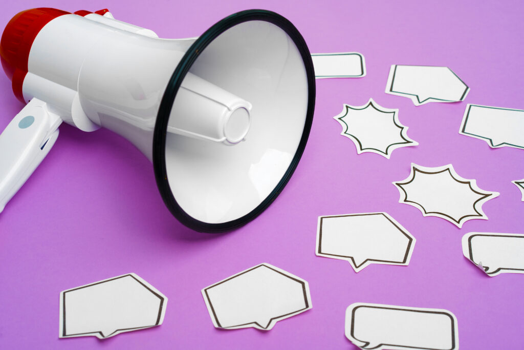 Electronic megaphone and speech bubble on purple color background